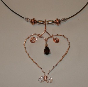 This wire wrapped heart by Heidi Danielson is made from copper and silver wire, with a garnet accent.